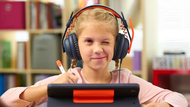 A younger student wearing the Logitech Zone Learn headphones in a school setting while working on a tablet device.