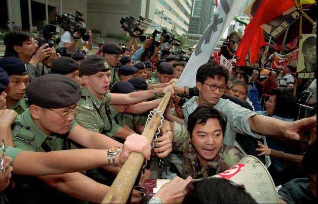 Pro-democracy activists scuffle with police officers outside the Hong Kong Conventional center to protest the visit of Chinese Foreign Minister Qian Qichen Friday, Nov. 15, 1996. The protesters said that Qian was the harbinger of "illegal" changes to Hong Kong 's political system. Qian convenes a meeting of 400 Hong Kong people who will choose the post-handover chief-executive in what pro-democracy activists say is a secretive and unfair process. (AP Photo/Vincent Yu)