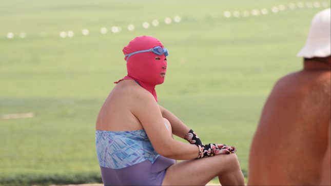 A masked female holidaymaker looks on at a beach resort on a scorching day in Qingdao city, east Chinas Shandong province, 3 July 2013. Holidaymakers are flooding to the beach resorts to cool down in the eastern Chinese coastal city of Qingdao as heat waves are sweeping through many parts of China. A group of female swimmers are spotlighted among the others as they dress their heads up with colorful masks, making them look like masked robbers or terrorists. Dubbed as the bikini for faces, the mask is used to protect the face of its user from being tanned by scorching sunlight and stung by jellyfish. Priced at 15-20 yuan (US$2.44-US$3.26) apiece, the mask is quite popular among middle-aged and elderly women.(Imaginechina via AP Images