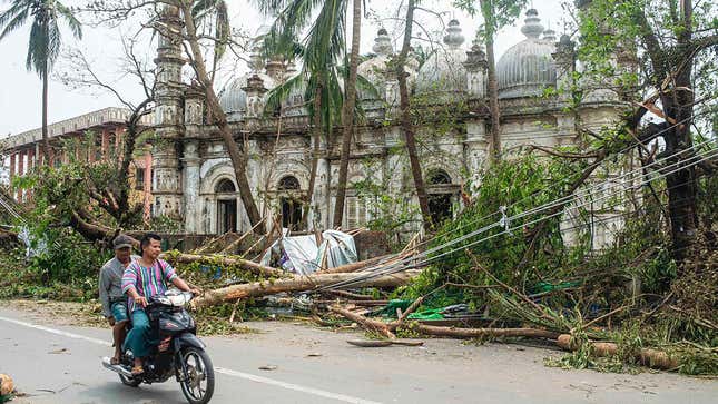 Riders bike past wreckage in Sittwe, Rakhine, Myanmar.