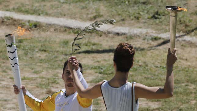 Greek actress Katerina Lehou, playing the role of High Priestess, passes the Olympic flame to the first torch bearer, Greek gymnast Eleftherios Petrounias (Reuters/Yannis Behrakis)
