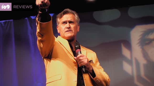 Evil Dead star Bruce Campbell stands onstage addressing fans at a horror convention.