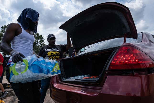 Residents distribute cases of water at Grove Park Community Center in Jackson, Mississippi, on September 3, 2022. - Jackson is enduring days without clean running water, with authorities urging those who still had supplies to shower with their mouths closed. The city, where 80 percent of the population is Black and poverty is rife, has been experiencing recurring water crises for years. But this week’s ordeal plunged Jackson into an emergency, with days of significant flooding disrupting the operation of a critical but aging water treatment plant. 
