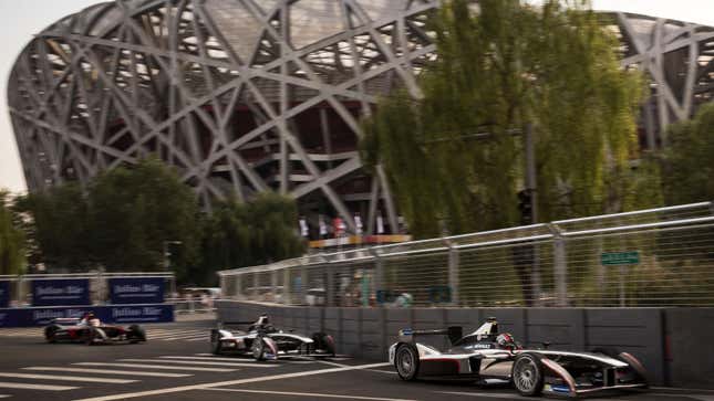 Formula E cars race past the Beijing Olympic Stadium