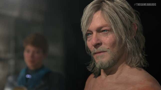 Norman Reedus' Death Stranding character Sam Porter Bridges looks at something offscreen while a blurry Lea Seydoux as Fragile is visible in the background.