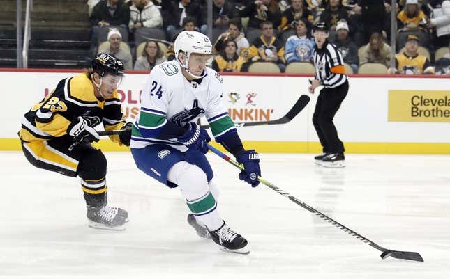 Jan 10, 2023; Pittsburgh, Pennsylvania, USA;  Vancouver Canucks defenseman Travis Dermott (24) moves the puck against Pittsburgh Penguins left wing Brock McGinn (23) during the first period at PPG Paints Arena. The Penguins won 5-4.