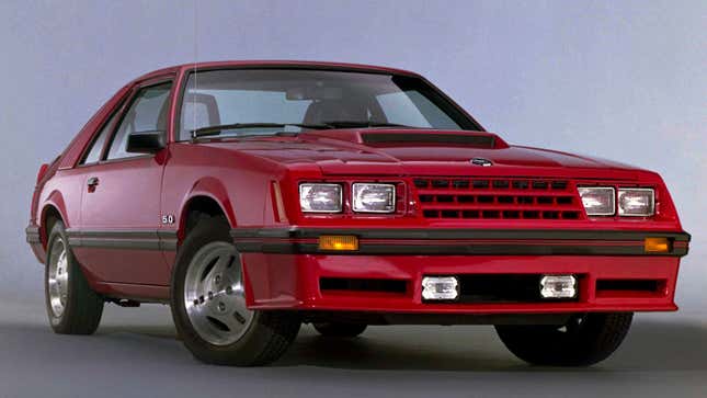 A photo of the front end on a red Fox Body Ford Mustang coupe. 
