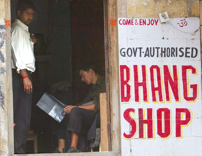 A foreign tourist reads the menu in a small wooden hut selling bhang in Jaisalmar,