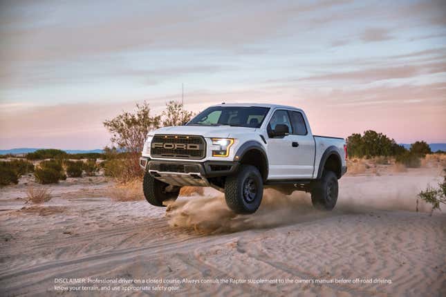 A white 2017 Ford F-150 Raptor jumps in the sand of a desert.