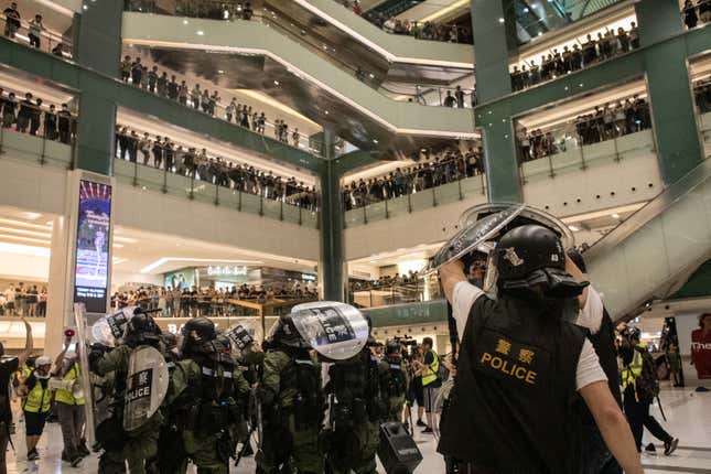 Riot police shield themselves as protesters throw objects at them as they chase protesters through a shopping mall on July 14, 2019 in Hong Kong.