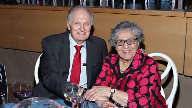 Alan Alda and Arlene Alda at a dinner table holding hands