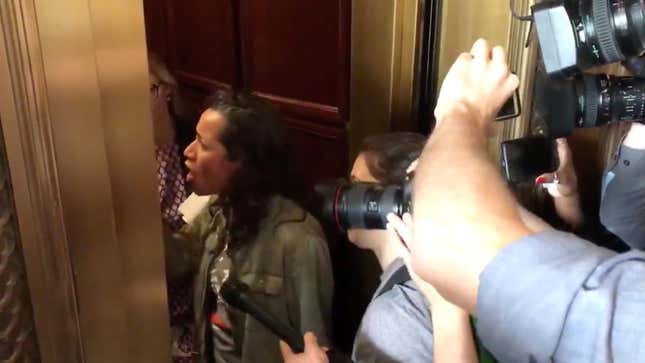 A protester steps into the elevator doorway to confront Flake.