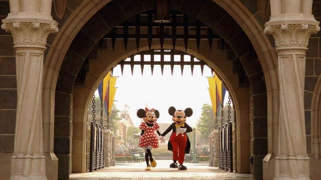 Mickey and Minnie Mouse standing under a threatening pointy metal gate at Disney World's Cinderella Castle
