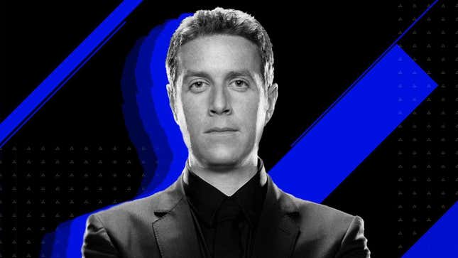 Game Awards host Geoff Keighley poses in a black suit in front of a blue and black background. 