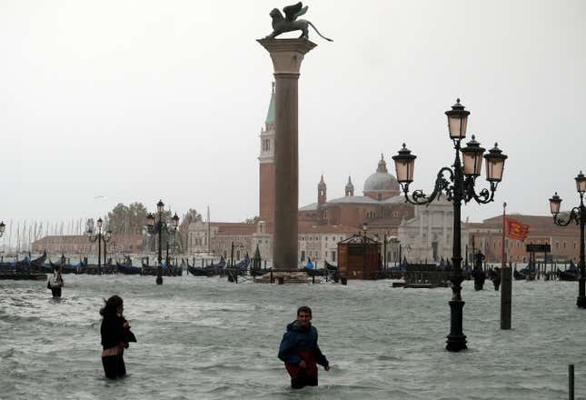 People walk in flooded Saint Mark Square during a period of seasonal high water in Venice