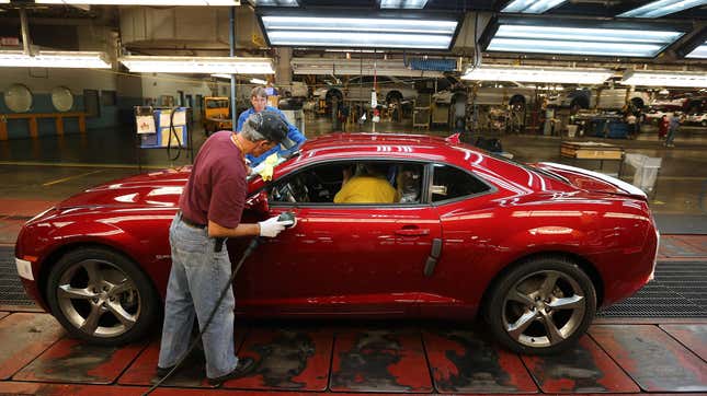 A red Chevrolet Camaro being detailed on an assembly line