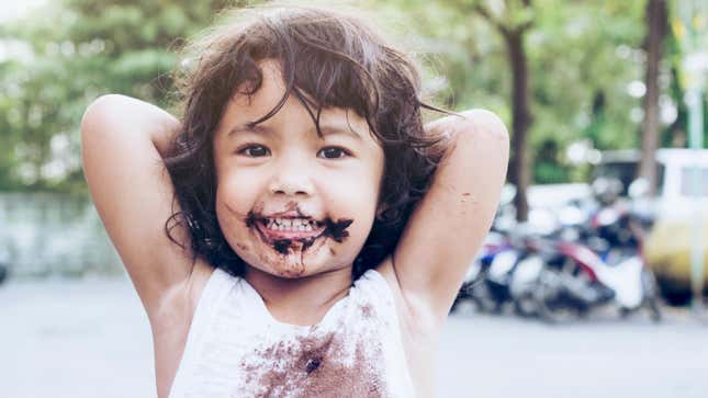 Young child with chocolate on their face and chocolate stains on their shirt.