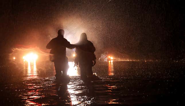 Sonoma County Fire’s Eric Gromala guides a woman to safety after her vehicle stalled out in deep floodwater near Forestville, California on March 9, 2023.