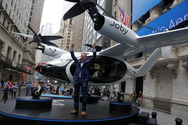 Joby Aviation founder JoeBen Bevirt poses next to a Joby Aviation Air Taxi with his fists raised in the air in front of the New York Stock Exchange