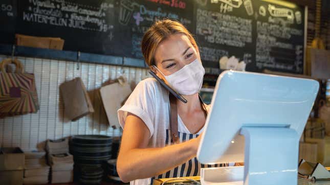 Front of house worker with mask confirming an order over the phone at a restaurant