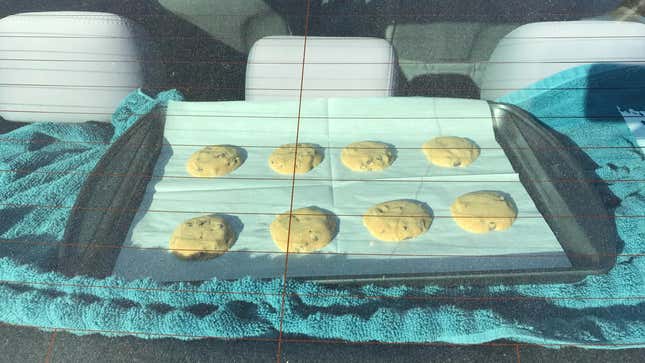Eight underbaked cookies on a tray sitting atop a towel inside a car.
