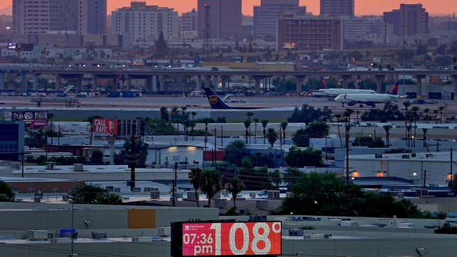 A sign displays an unofficial temperature as jets taxi at Sky Harbor International Airport at dusk, July 12, 2023, in Phoenix. 