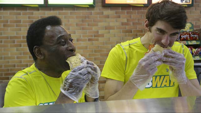 Former U.S. Olympic Swimmer Michael Phelps, right, and Brazilian soccer legend Pele, left, eat sandwiches at a SUBWAY restaurant, during a event organized by SUBWAY, on Wednesday, Dec. 4, 2013 in Sao Paulo, Brazil. (Photo by Nelson Antoine/Invision for SUBWAY Restaurants/AP Images)