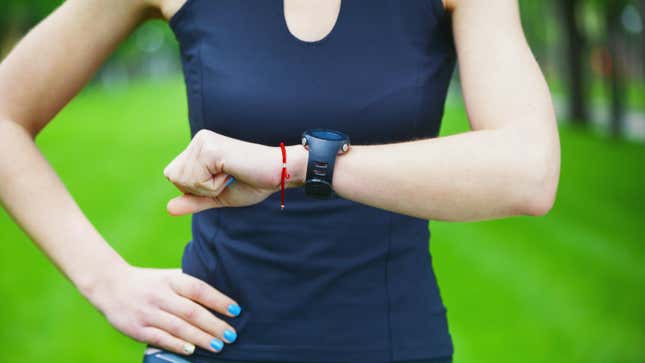 A woman in workout gear viewed from the shoulders down checks her fitness smartwatch