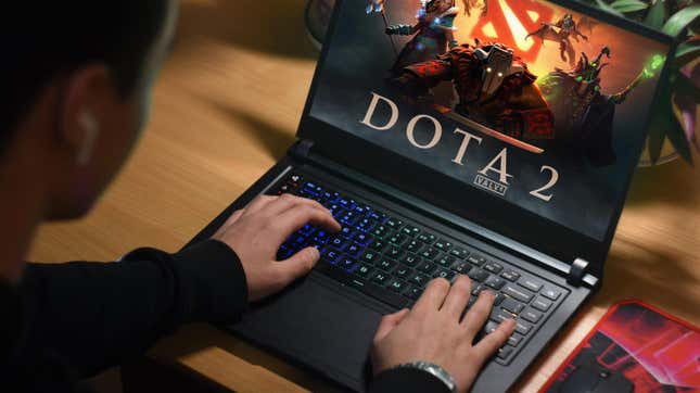 A person plays Dota 2 on a laptop