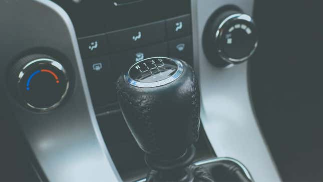 A photo of a manual gear shifter wrapped in black leather. 