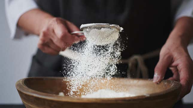 A woman sifts flour