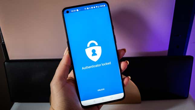 A photo of a person holding up an Android phone with the Authenticator app on screen