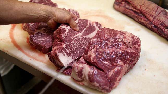 Person cuts into slab of raw steak