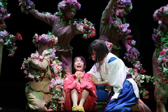Chihiro crying and being comforted by Haku while surrounded by flower people