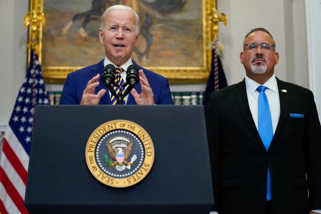 President Joe Biden speaks about student loan debt forgiveness in the Roosevelt Room of the White House, Aug. 24, 2022, in Washington. Education Secretary Miguel Cardona listens at right. 