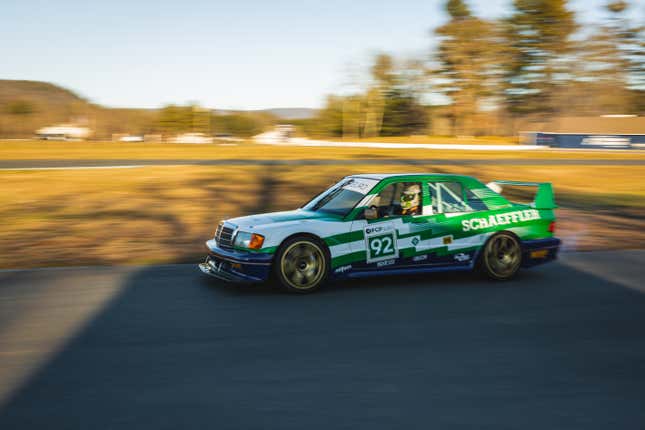 A green, white and blue racing liveried Mercedes 190e drives on track.