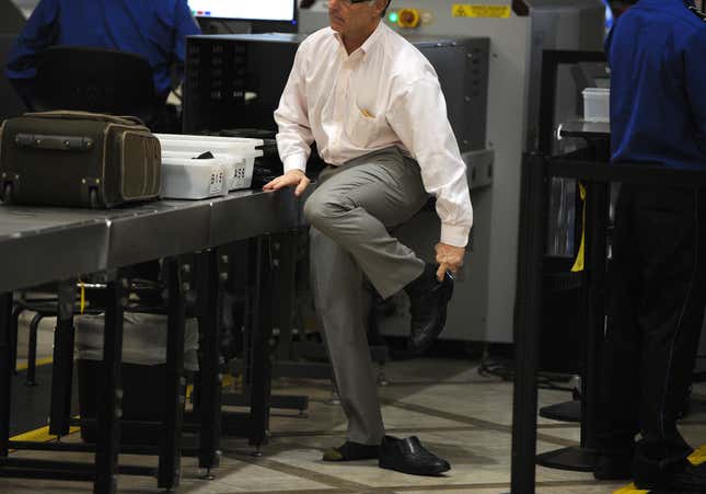 An air traveler puts his shoes back on after passing through the Transportation Security Administration (TSA) security check at Los Angeles International Airport (LAX) on February 20, 2014 in Los Angeles, California.