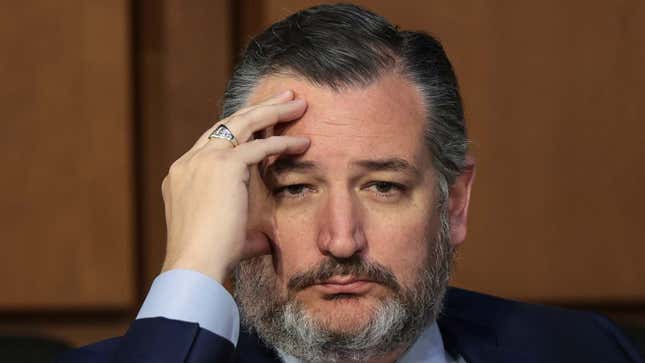 Ted Cruz looks directly at the camera while he holds his head with his right hand. 