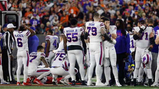 Buffalo Bills players console each other as Damar Hamlin is taken away via ambulance after he collapsed on the field.
