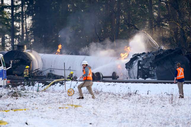 A firefighter sprays foam on a burning rail car.