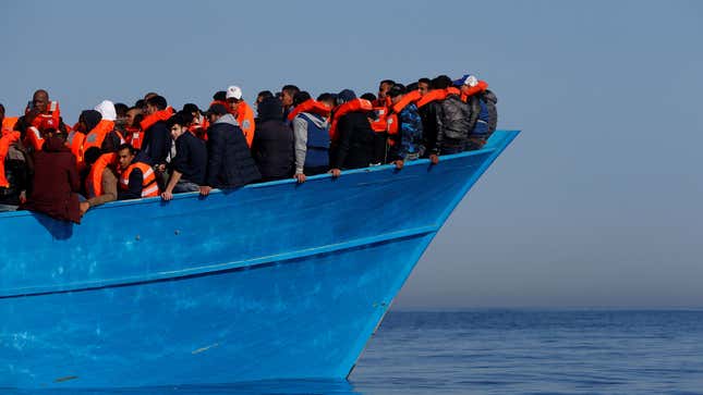 Migrants on a wooden boat await rescue by the Malta-based NGO Migrant Offshore Aid Station (MOAS) in the central Mediterranean