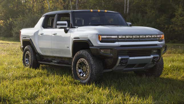 A photograph of a silver 2022 GMC Hummer EV parked in a field of grass.