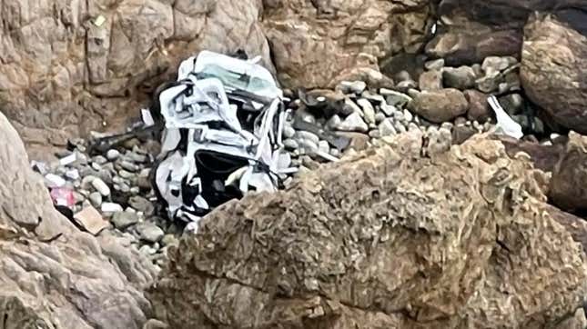 Wreckage of a white Tesla Model S sits at the bottom of a rocky ravine after falling 330-feet.