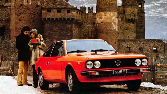 A photo of a red Lancia Beta coupe parked in front of a castle. 