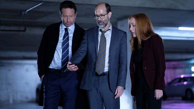 X-Files agents Fox Mulder and Dana Scully stand with Reggie in a large parking garage in "The Lost Art of Forehead Sweat."