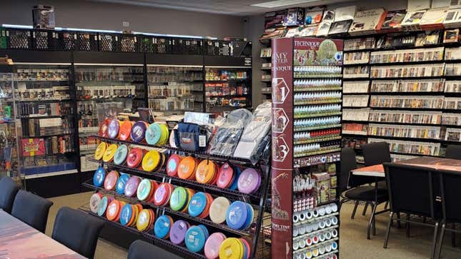 Inside Cosmic Games, featuring packed shelves and paint for miniatures.