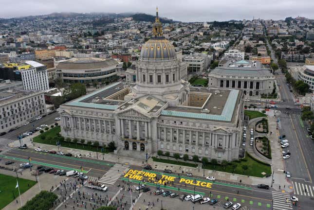 "Defund the police" is written in bold yellow letters on the road outside of San Francisco's greco-roman City Hall.