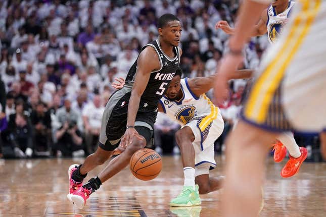 Apr 15, 2023; Sacramento, California, USA; Sacramento Kings guard De&#39;Aaron Fox (5) dribbles past Golden State Warriors forward Andrew Wiggins (22) in the first quarter during game one of the 2023 NBA playoffs at the Golden 1 Center.