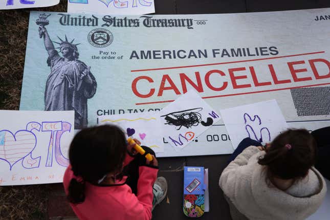 WASHINGTON, DC - DECEMBER 13: Children draw on top of a ‘canceled check’ prop during a rally in front of the U.S. Capitol on December 13, 2021, in Washington, DC. 