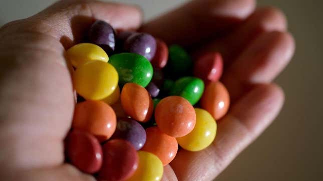 Hand holding pile of Skittles candy